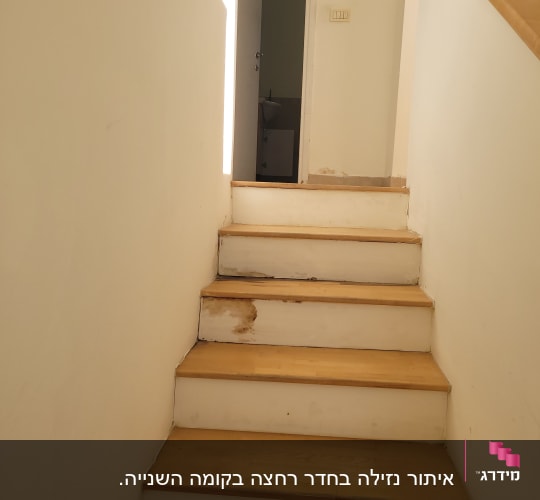 מדרגות עץ עם סימני רטיבות בקיר ובמדרגה